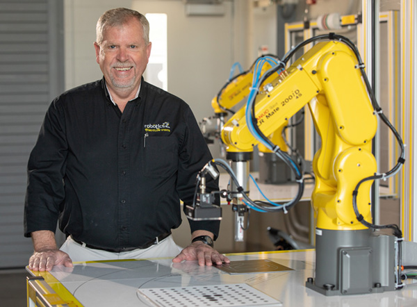 portrait of Charlie King with a FANUC robot